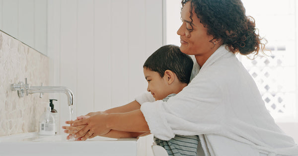 A mother and child washing their hands together.