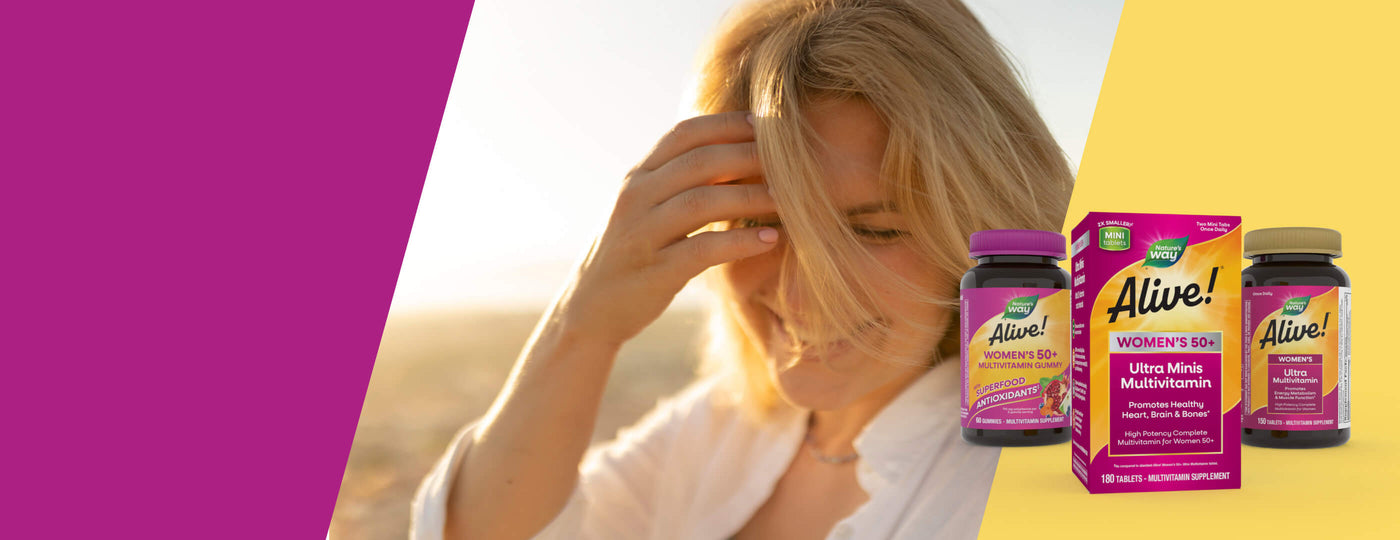 Woman with blonde hair and a white coat standing on a beach, with Nature's Way Alive! multivitamin bottles displayed.
