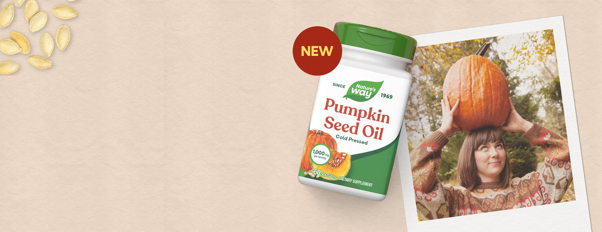 A bottle of Pumpkin Seed Oil with a green cap and white label, shown on a beige background next to a printed photo of a woman balancing a pumpkin and a red 'NEW' badge.