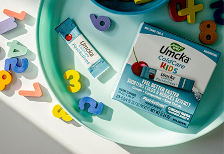 <{%DETAIL1_60166%}>Umcka Cold Care Kids packaging on a tray surrounded by magnetic letters and numbers
