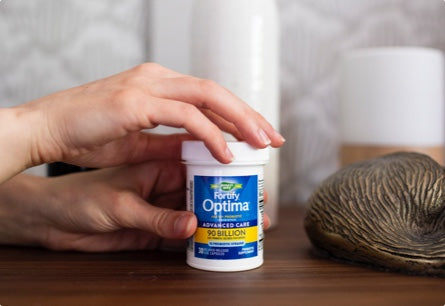 <{%DETAIL1_15785%}>Hands opening a bottle of Fortify Optima 50 Plus Daily Probiotic.