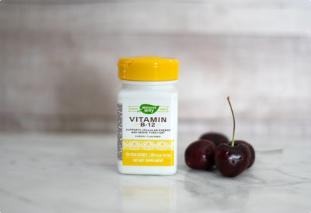 <{%DETAIL1_40440%}>A bottle of Vitamin B-12 sitting on a table next to cherries.