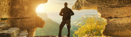 Man standing at the top of a cliff on a hike.