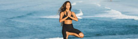 Woman doing yoga in front of the ocean.