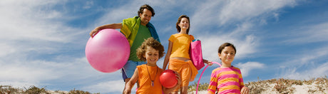 Family at the beach with toys and towels.