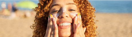 Woman smiling putting sunscreen on her face.