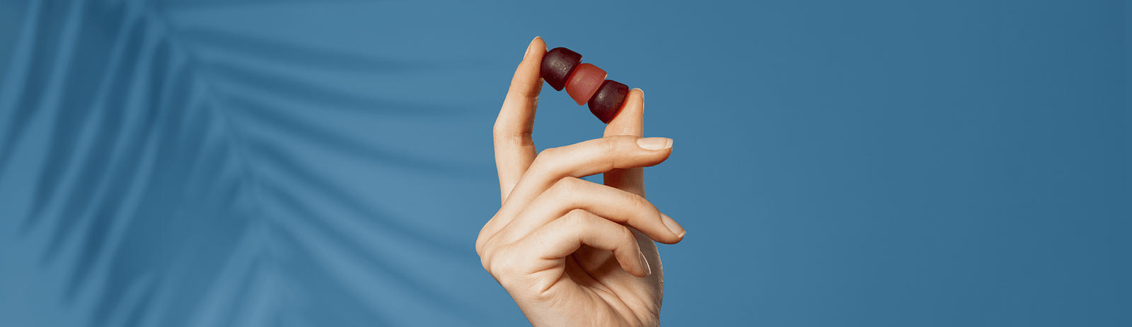 A hand holding three gummies.
