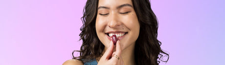 Woman smiling about to eat Juicy Burst chew on purple background