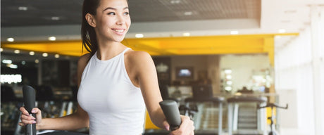 A smiling woman using exercise equipment in a gym.