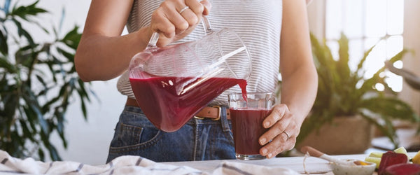 A woman pouring juice into a glass.