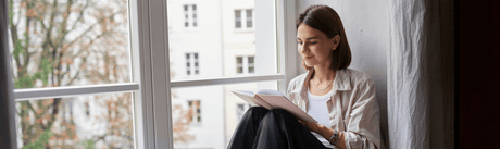 Woman writing and reading on a window sill