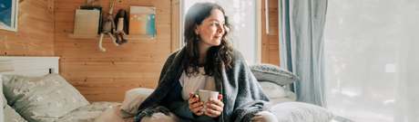 woman holding mug in bed