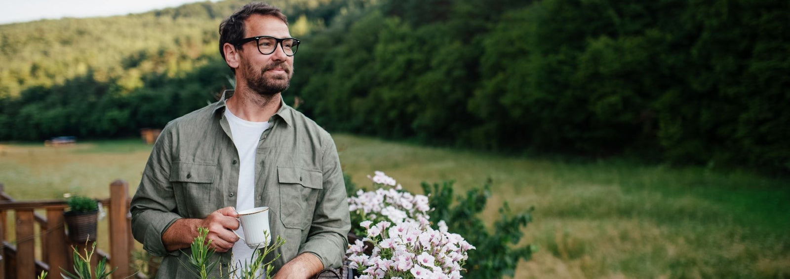 man holding coffee next to flowers