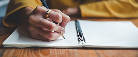 A hand writing in a notebook.