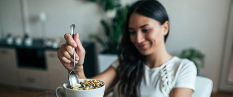 A smiling woman eating a healthy breakfast.