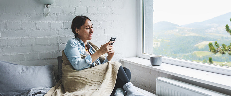 A woman sitting on a couch looking at her phone.