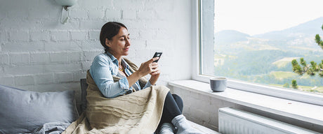 A woman sitting on a couch looking at her phone.