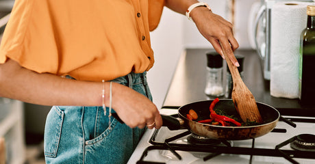 A person stirring vegetables in a pan.