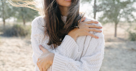 A woman hugging herself outside.