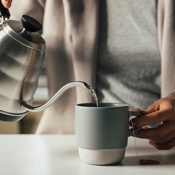 A woman pouring water into a cup.