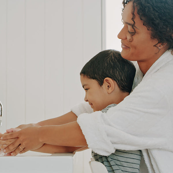 A mother and child washing their hands together.