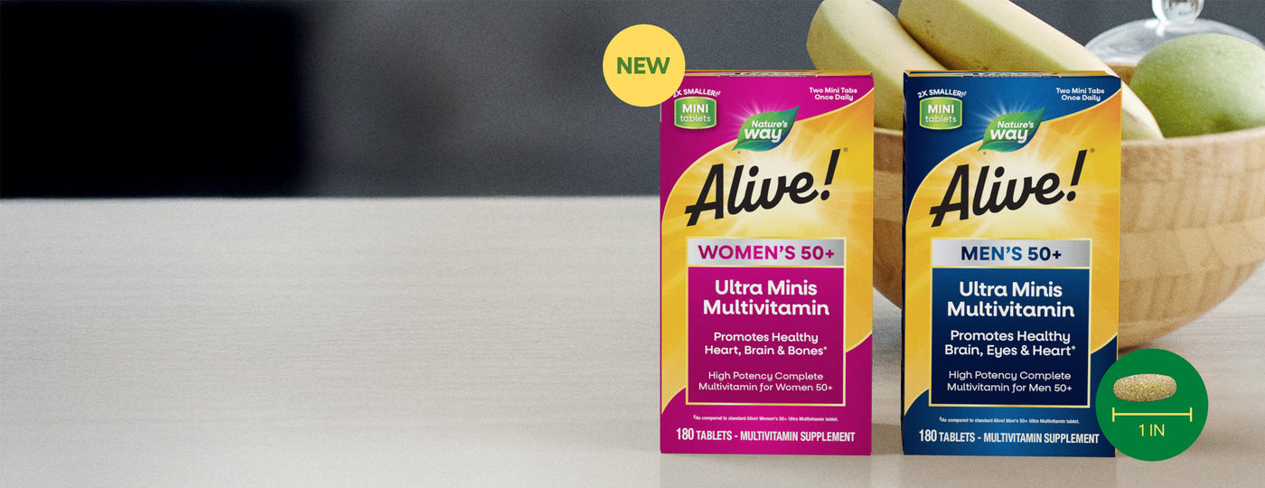 Two boxes of 'Alive!' mini ultra multivitamins, one for women and one for men, with bananas and a green apple in the background.