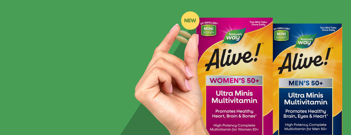 Hand holding two 'Alive!' ultra mini multivitamin packages against a green background
