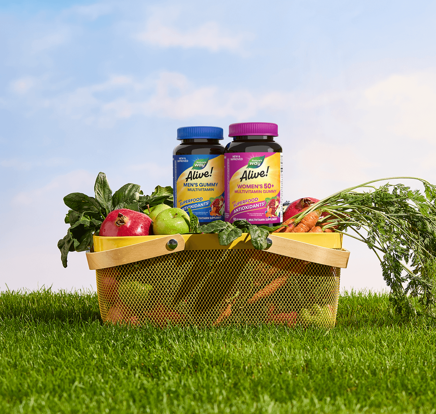 Bottles of Alive! Men's and Women's Gummies perched in a picnic basket on a green lawn