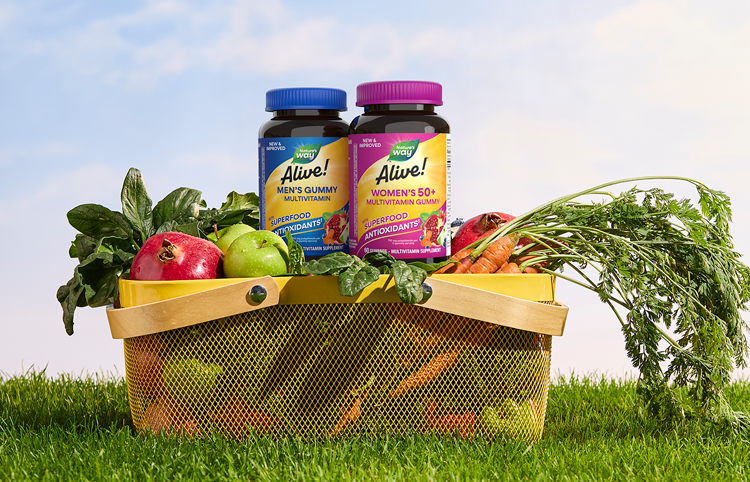 Bottles of Alive! Men's and Women's Gummies perched in a picnic basket on a green lawn