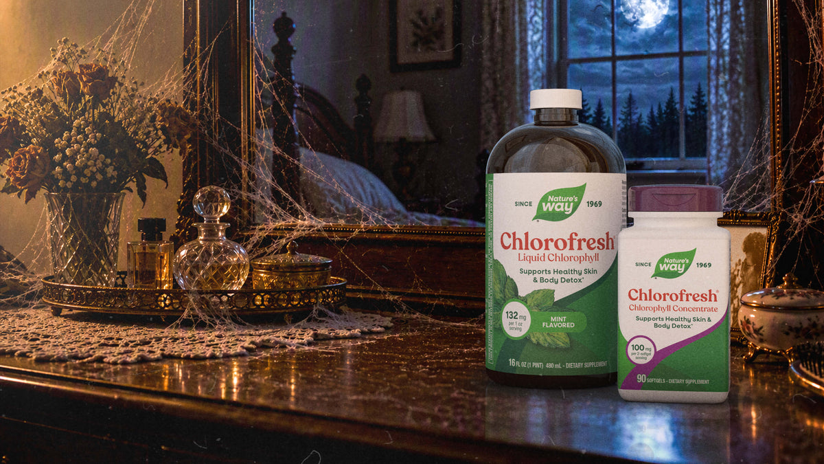 Two bottles of Chlorofresh dietary supplements placed on a dark wooden table in front of a spooky window scene with a full moon and spiderwebs.