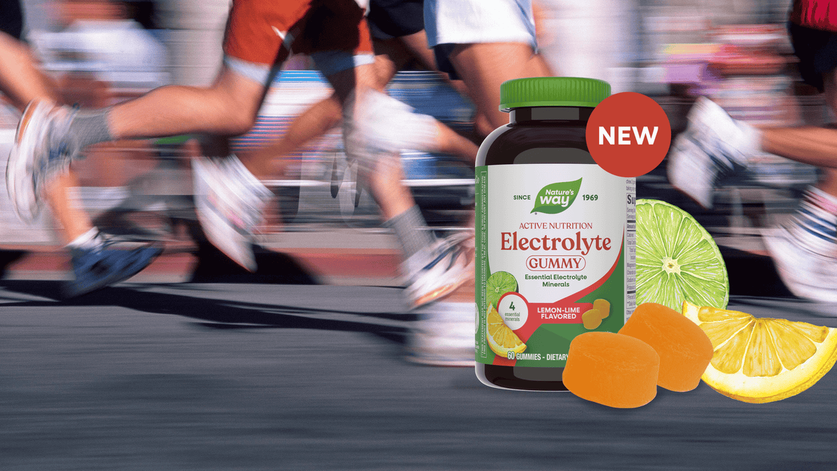 A bottle of Active Nutrition Electrolyte Gummies (Lemon-Lime Flavor) is shown in the foreground with gummy candies and citrus slices, set against a blurred background of running marathon participants.