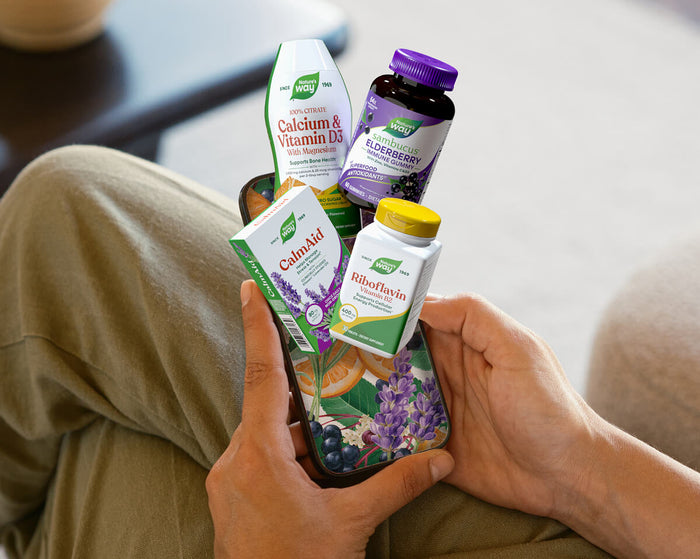 A person holding a small basket filled with several supplement products, while sitting indoors.