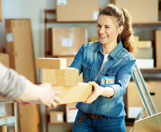 Woman handing another individual three shipping boxes