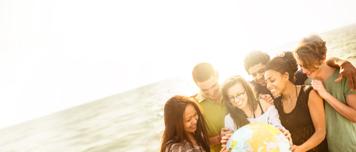 Group of people on a beach holding a global beach ball