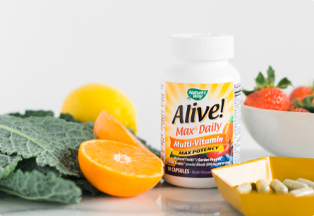 <{%DETAIL1_15090%}>A bottle of Alive Max Daily Multi-vitamin sitting next to fruits and vegetables.