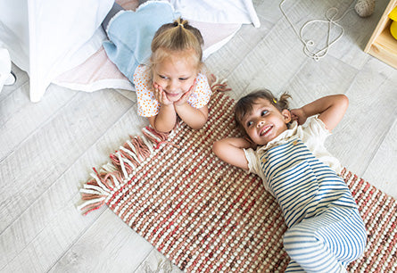 <{%DETAIL2_13670%}>Two children lounging on the floor smiling
