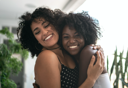 Two women smiling and hugging. 