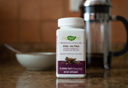 A bottle of DGL Ultra sitting on a couner in front of a bowl and a french press.
