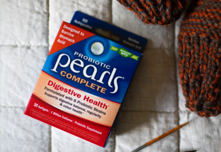 A package of Probiotic Pearls Complete Digestive Health laying next to yarn and knitting needles.