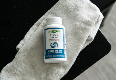 A bottle of Fisol Fish Oil laying on a towel.