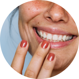A smiling woman with her fingers on her lips.