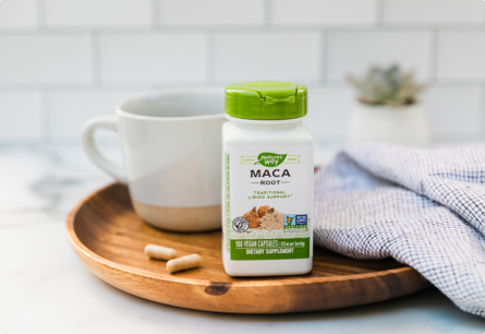 A bottle of Maca Root on a tray next to a coffee mug and a kitchen towel.