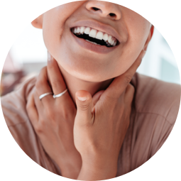 A smiling woman touching her throat.