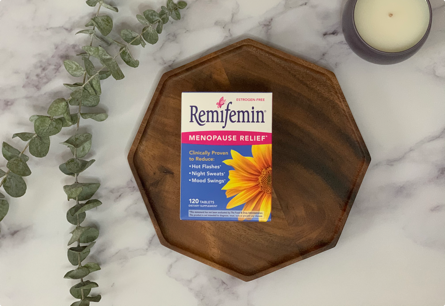 <{%DETAIL1_07520%}>A package of Remifemin Menopause Relief laying next to a plant and a candle.