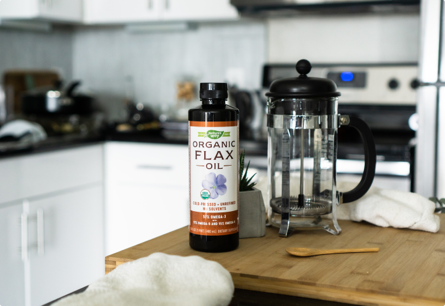 A bottle of Organic Flax OIl sitting next to a french press.