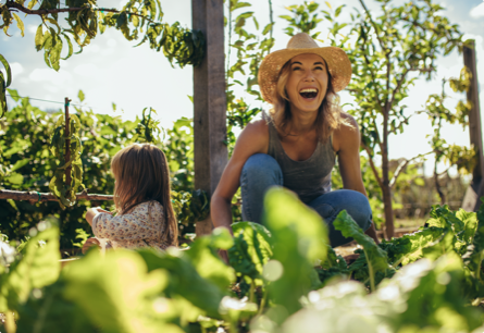 <{%DETAIL2_15604%}>A laughing woman wearing a straw hat and a child in a garden.