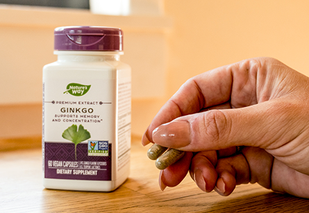 <{%DETAIL1_61600%}>A bottle of Nature's Way Ginkgo is next to a hand holding two capsules